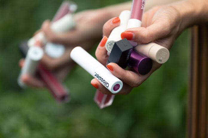 Hand clutching multiple cosmetic lip products