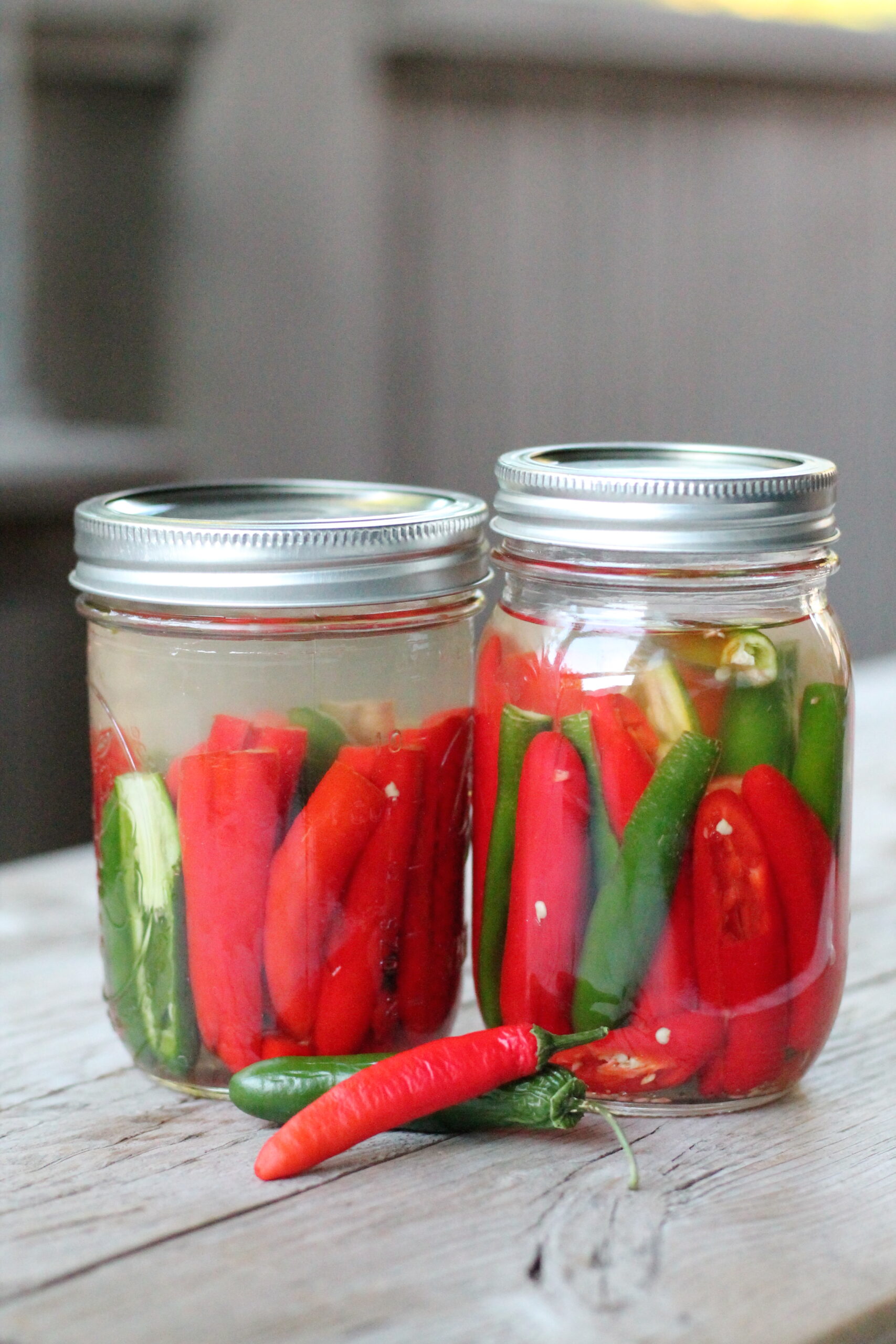 Two jars of red and green hot peppers
