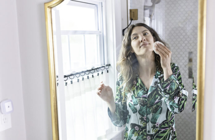 woman-removing-makeup-in-mirror