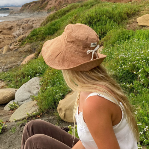 gardening hat for women in linen fabric. model is outside in nature. 