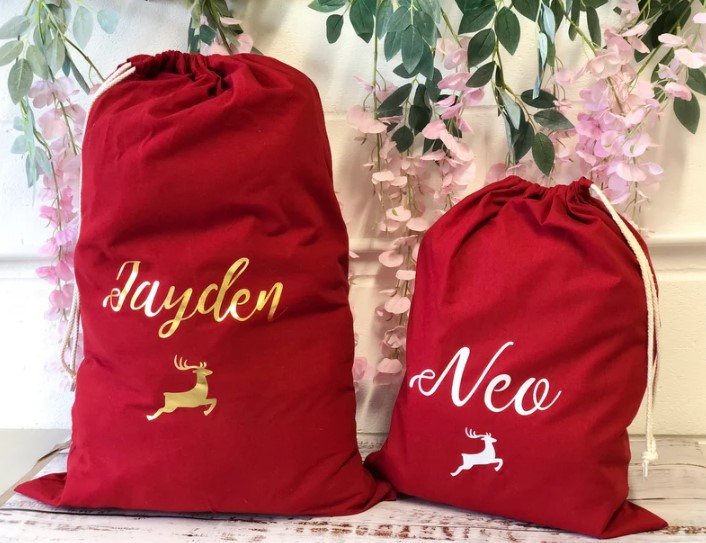 Eco-Friendly Christmas Wrapping Paper - red fabric sacks with monogrammed names and a reindeer flying